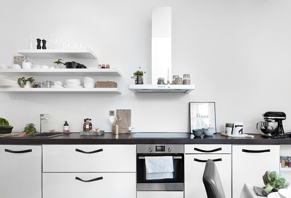 Foto på ett mellanstort skandinaviskt linjärt kök och matrum, med en nedsänkt diskho, släta luckor, rostfria vitvaror och granitbänkskiva