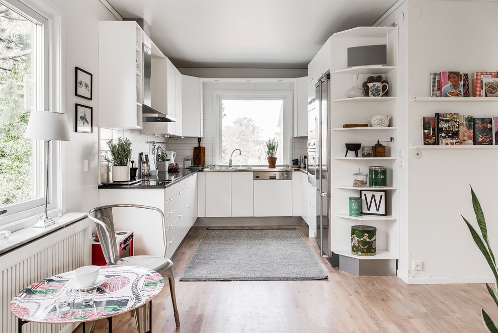 На фото: п-образная кухня-гостиная в скандинавском стиле с плоскими фасадами и белыми фасадами без острова