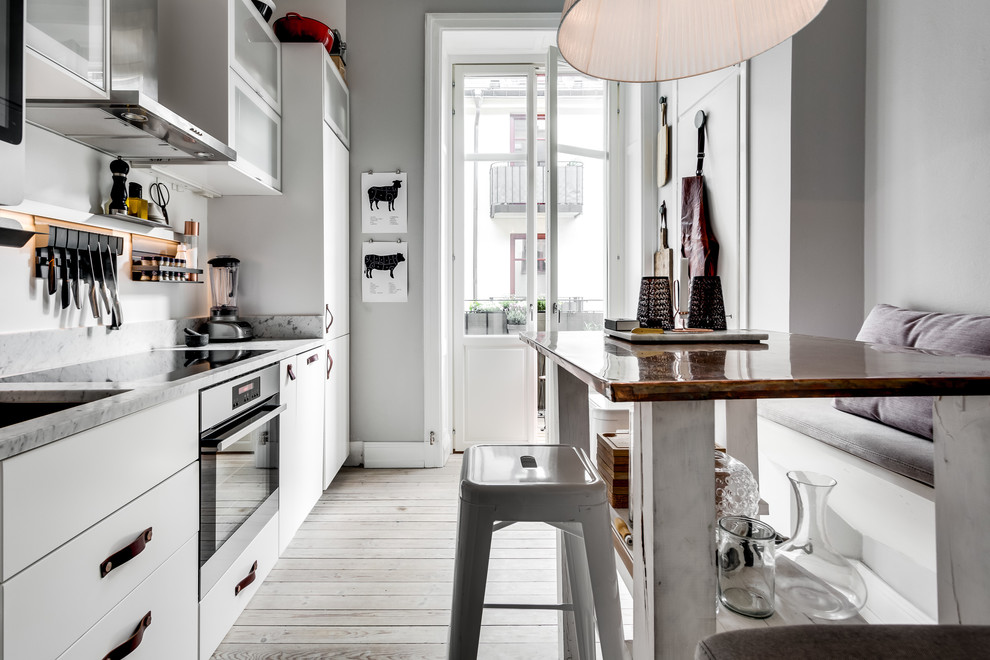 Inredning av ett nordiskt mellanstort linjärt kök och matrum, med släta luckor, vita skåp, marmorbänkskiva, integrerade vitvaror och ljust trägolv