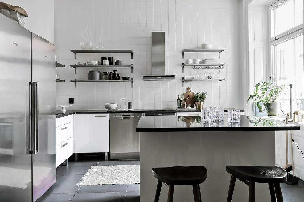 Bild på ett nordiskt kök, med vita skåp, vitt stänkskydd, en köksö och grått golv