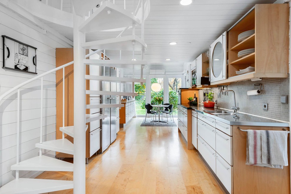 Idéer för att renovera ett skandinaviskt kök, med en integrerad diskho, släta luckor, vita skåp, bänkskiva i rostfritt stål, grått stänkskydd, stänkskydd i mosaik, rostfria vitvaror, ljust trägolv och beiget golv
