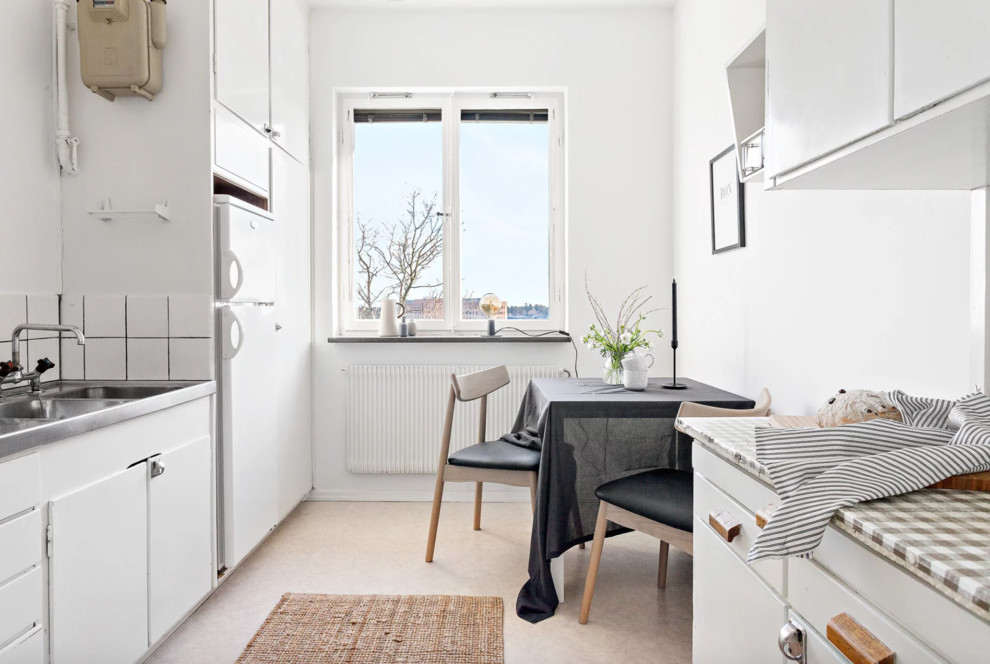 Idéer för små minimalistiska flerfärgat kök, med en dubbel diskho, släta luckor, vita skåp, bänkskiva i rostfritt stål, vitt stänkskydd, vita vitvaror, korkgolv och beiget golv