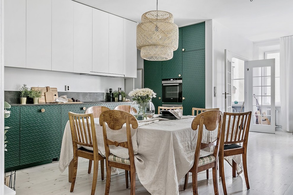 Photo of a medium sized scandi single-wall open plan kitchen in Stockholm with a single-bowl sink, beaded cabinets, green cabinets, granite worktops, black splashback, integrated appliances, light hardwood flooring, no island and beige floors.