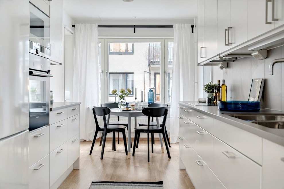 Idéer för ett skandinaviskt grå kök, med en dubbel diskho, släta luckor, grått stänkskydd, rostfria vitvaror, mellanmörkt trägolv och brunt golv