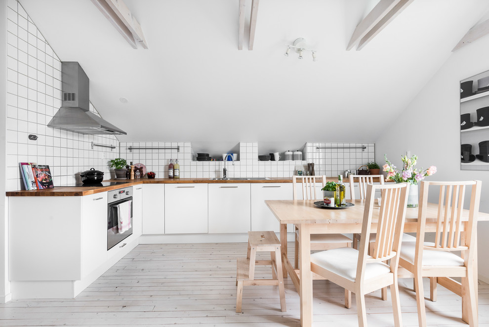 Immagine di una cucina scandinava con lavello da incasso, ante lisce, ante bianche, top in legno, paraspruzzi bianco, elettrodomestici in acciaio inossidabile, pavimento in legno verniciato e nessuna isola