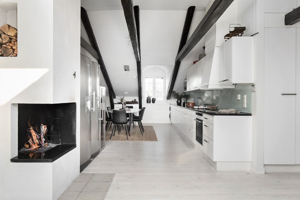 Idee per una cucina scandinava di medie dimensioni con ante bianche, top in granito, top nero, ante lisce, paraspruzzi grigio, paraspruzzi con lastra di vetro, parquet chiaro e pavimento beige