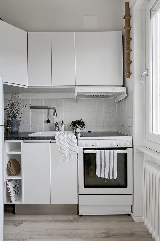 ストックホルムにある小さな北欧スタイルのおしゃれなキッチン (フラットパネル扉のキャビネット、白いキッチンパネル、白い調理設備) の写真