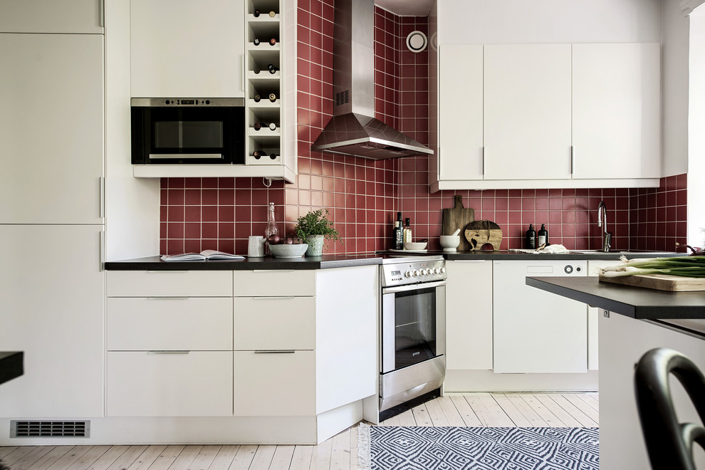 На фото: кухня среднего размера в скандинавском стиле с плоскими фасадами, белыми фасадами, красным фартуком, светлым паркетным полом и бежевым полом