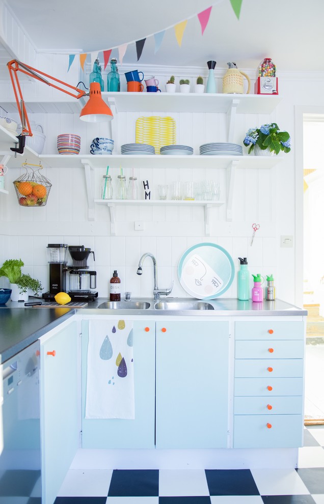 Kleine Skandinavische Küche ohne Insel in L-Form mit integriertem Waschbecken, flächenbündigen Schrankfronten, blauen Schränken, Edelstahl-Arbeitsplatte, Küchenrückwand in Weiß, Rückwand aus Keramikfliesen und Keramikboden in Sonstige