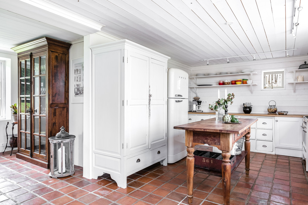 Foto på ett avskilt, mellanstort lantligt u-kök, med släta luckor, vita skåp, träbänkskiva och en köksö