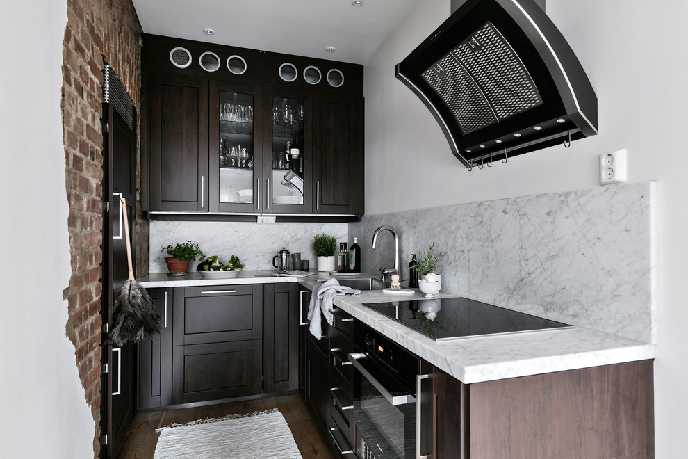 Foto på ett litet minimalistiskt grå kök, med luckor med glaspanel, skåp i mörkt trä, marmorbänkskiva, grått stänkskydd, stänkskydd i marmor, en nedsänkt diskho, svarta vitvaror, mellanmörkt trägolv och brunt golv