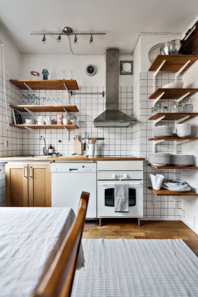 Diseño de cocina lineal urbana pequeña abierta con puertas de armario de madera oscura, encimera de madera, salpicadero blanco, salpicadero de azulejos de vidrio y suelo de madera en tonos medios
