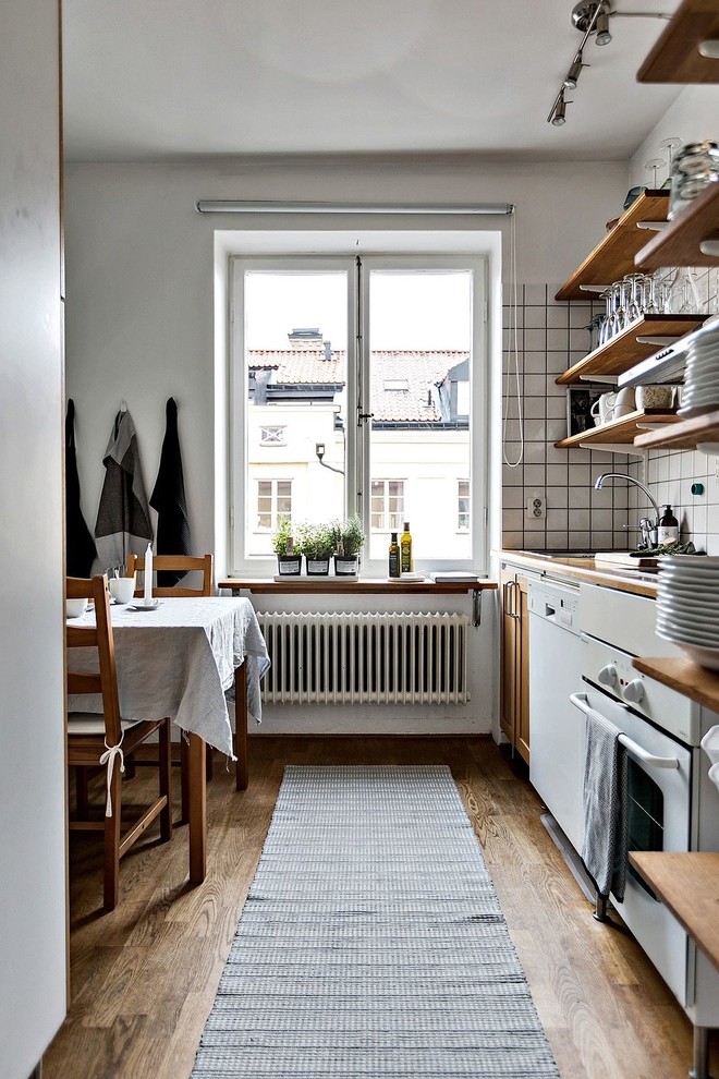 Imagen de cocina urbana de tamaño medio con armarios abiertos, salpicadero blanco y suelo de madera oscura