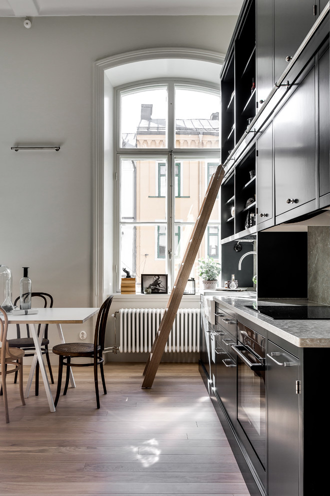 Esempio di una cucina scandinava di medie dimensioni con lavello da incasso, ante grigie, top in pietra calcarea, elettrodomestici da incasso e pavimento in legno massello medio