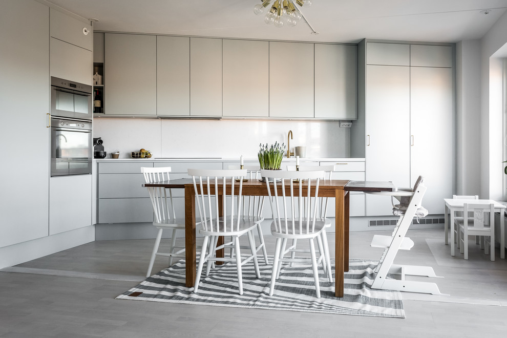 Skandinavische Wohnküche mit flächenbündigen Schrankfronten, grauen Schränken und Küchenrückwand in Weiß in Stockholm