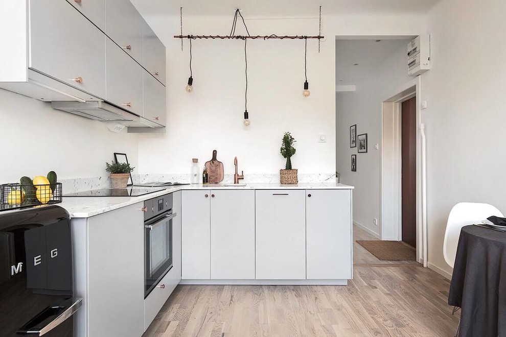 Foto på ett stort funkis kök, med en enkel diskho, släta luckor, grå skåp, marmorbänkskiva, svarta vitvaror och ljust trägolv
