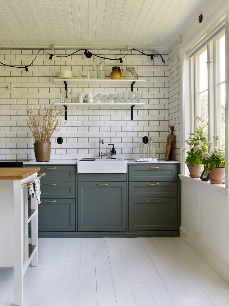 Einzeilige, Mittelgroße Nordische Küche mit Waschbecken, Schrankfronten im Shaker-Stil, grünen Schränken, Küchenrückwand in Weiß, gebeiztem Holzboden und Kücheninsel in Stockholm