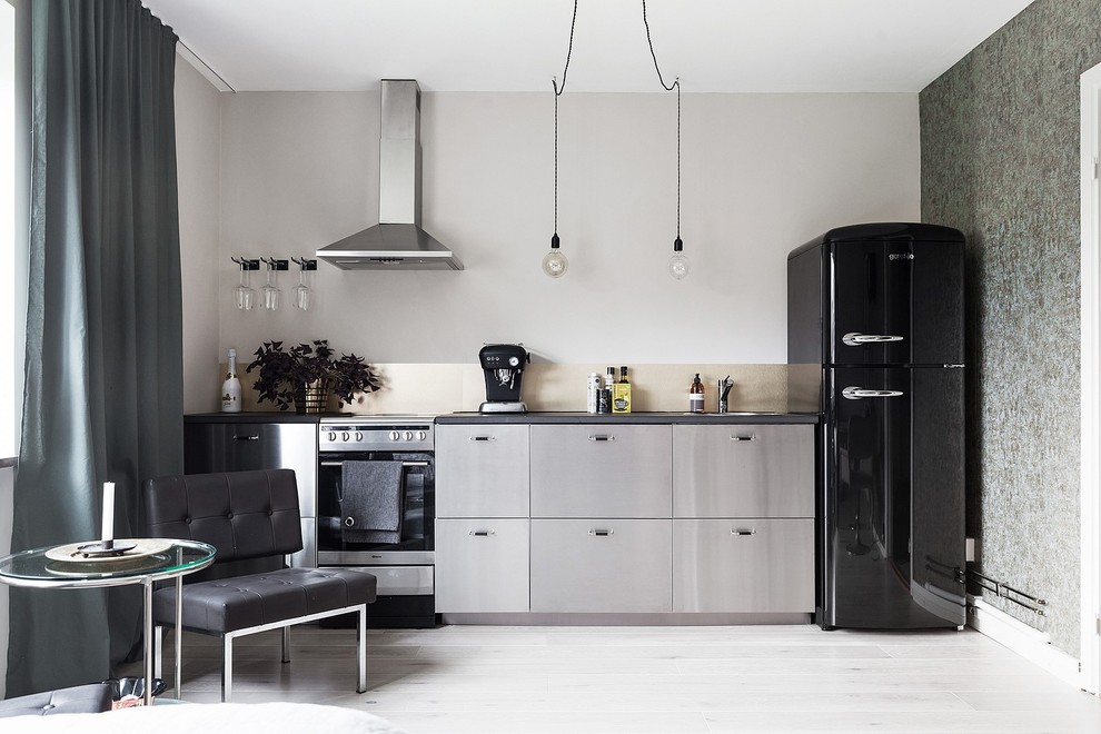 Cette photo montre une petite cuisine ouverte linéaire scandinave en inox avec un placard à porte plane, une crédence métallisée, parquet clair et aucun îlot.