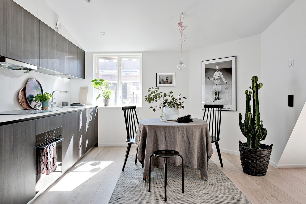 Inspiration for a medium sized scandi single-wall kitchen/diner in Gothenburg with flat-panel cabinets, dark wood cabinets, black appliances, light hardwood flooring and no island.