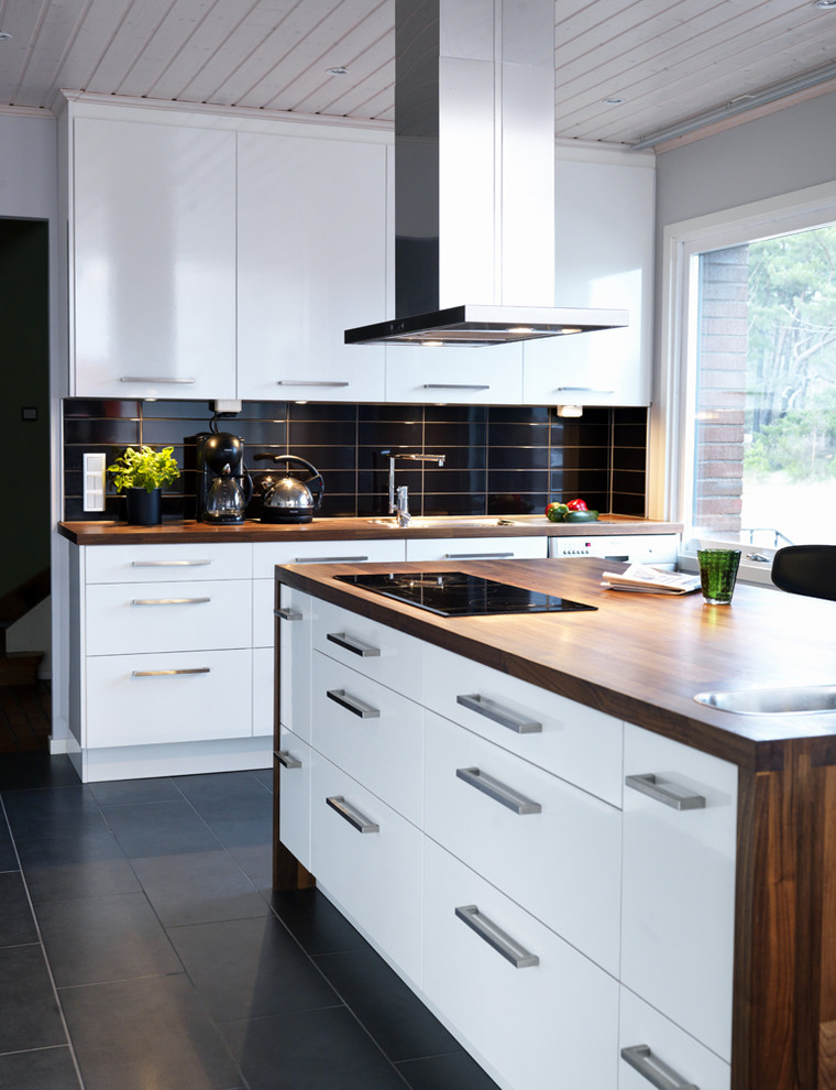 Mittelgroße Moderne Küche mit flächenbündigen Schrankfronten, weißen Schränken, Arbeitsplatte aus Holz, Kalkstein und Kücheninsel in Örebro