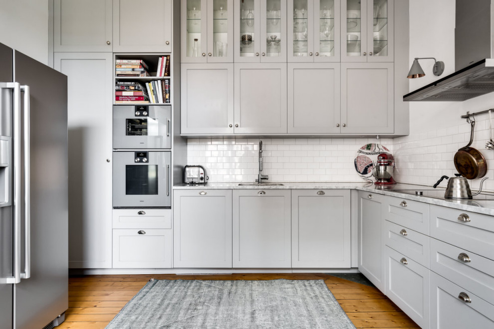 Idéer för att renovera ett mellanstort vintage vit vitt kök, med en nedsänkt diskho, luckor med profilerade fronter, grå skåp, marmorbänkskiva, vitt stänkskydd, stänkskydd i keramik, rostfria vitvaror, mellanmörkt trägolv och beiget golv