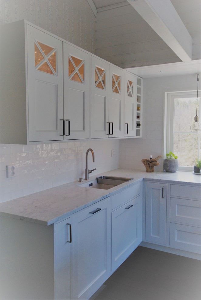 Inspiration for a large victorian l-shaped eat-in kitchen remodel in Stockholm with a single-bowl sink, beaded inset cabinets, white cabinets, marble countertops, black appliances, an island and white countertops