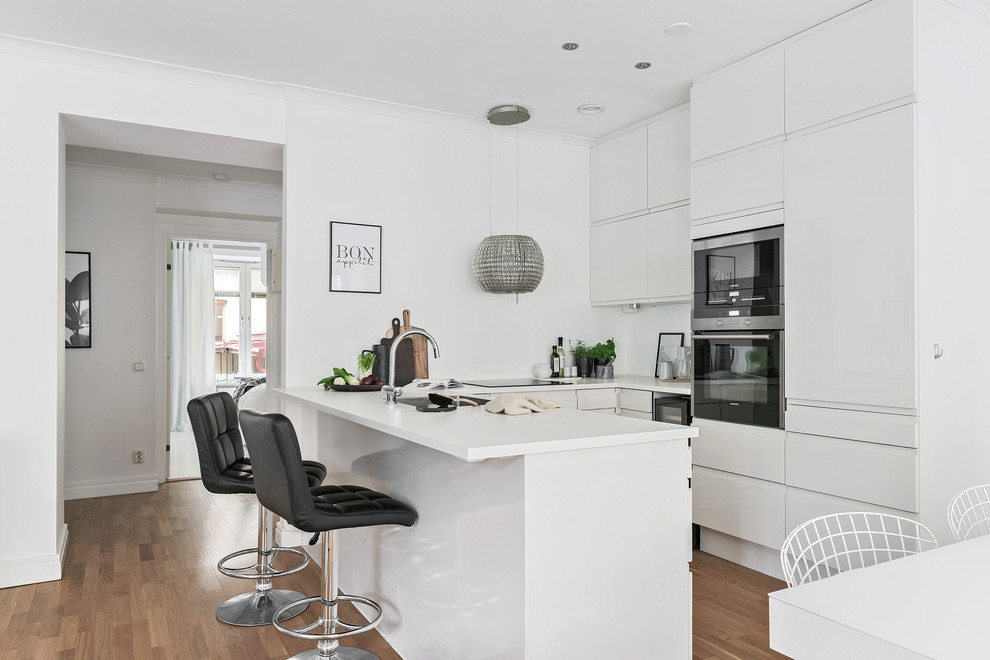 Источник вдохновения для домашнего уюта: п-образная кухня среднего размера в стиле модернизм с обеденным столом, плоскими фасадами, белыми фасадами и полуостровом