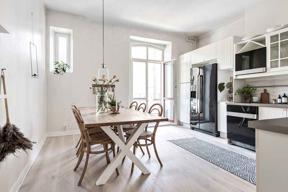 Foto de cocina nórdica grande sin isla con puertas de armario blancas y electrodomésticos negros