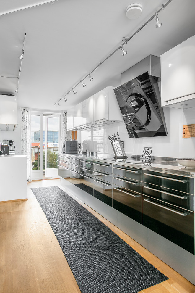 Example of a mid-sized trendy single-wall open concept kitchen design in Malmo with flat-panel cabinets, black cabinets, white backsplash and no island