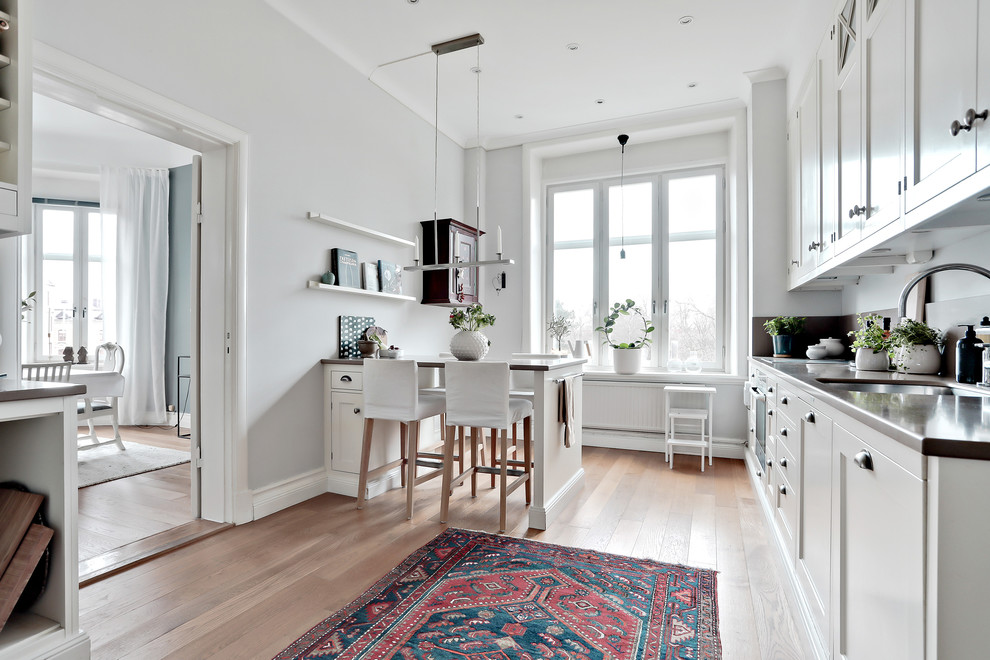 Design ideas for a large scandinavian kitchen in Gothenburg with recessed-panel cabinets, white cabinets and a breakfast bar.
