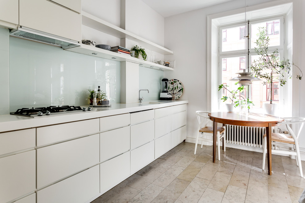 Modelo de cocina comedor lineal escandinava sin isla con armarios con paneles lisos, puertas de armario blancas, salpicadero blanco, salpicadero de vidrio templado y suelo beige