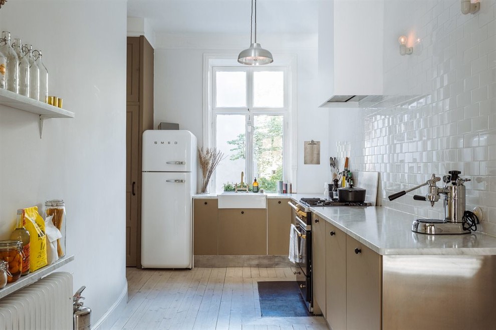 Mittelgroße Skandinavische Küche ohne Insel in L-Form mit Waschbecken, flächenbündigen Schrankfronten, beigen Schränken, Marmor-Arbeitsplatte, weißen Elektrogeräten und hellem Holzboden in Stockholm