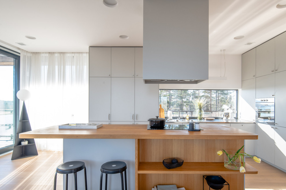 Idéer för ett modernt grå l-kök, med släta luckor, grå skåp, rostfria vitvaror, mellanmörkt trägolv, en köksö och brunt golv