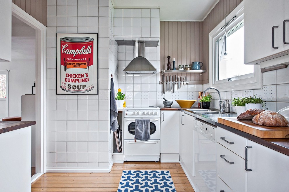 Ispirazione per una cucina scandinava di medie dimensioni con lavello a doppia vasca, ante lisce, ante bianche, paraspruzzi bianco, elettrodomestici bianchi e pavimento in legno massello medio