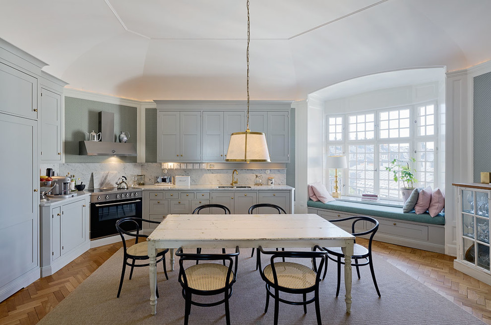 Mittelgroße Klassische Wohnküche ohne Insel in L-Form mit Schrankfronten im Shaker-Stil, blauen Schränken, Küchenrückwand in Weiß, Küchengeräten aus Edelstahl und braunem Holzboden in Stockholm