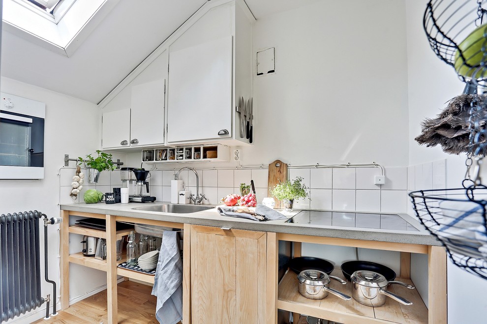 Idéer för mellanstora nordiska linjära kök, med en nedsänkt diskho, släta luckor, vita skåp, vitt stänkskydd och mellanmörkt trägolv