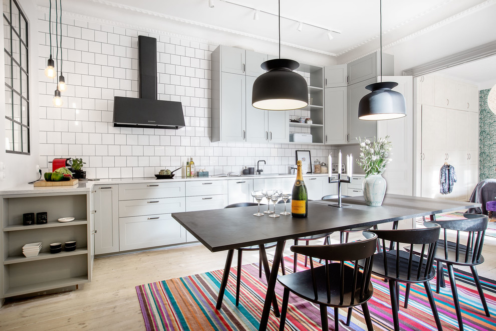 Große Nordische Wohnküche ohne Insel in L-Form mit Schrankfronten im Shaker-Stil, grauen Schränken, Küchenrückwand in Weiß und hellem Holzboden in Stockholm