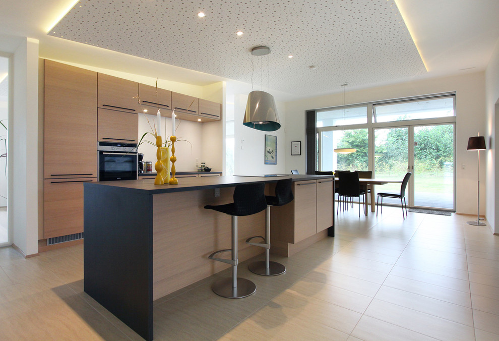 Einzeilige Moderne Küche mit flächenbündigen Schrankfronten, hellen Holzschränken, Küchenrückwand in Weiß, Kücheninsel und beigem Boden in Aarhus