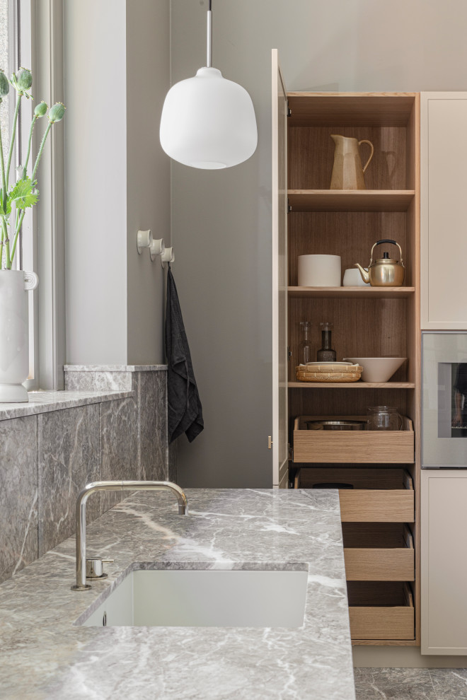 Skandinavisk inredning av ett stort grå linjärt grått kök med öppen planlösning, med en enkel diskho, beige skåp, marmorbänkskiva, marmorgolv, en köksö och grått golv