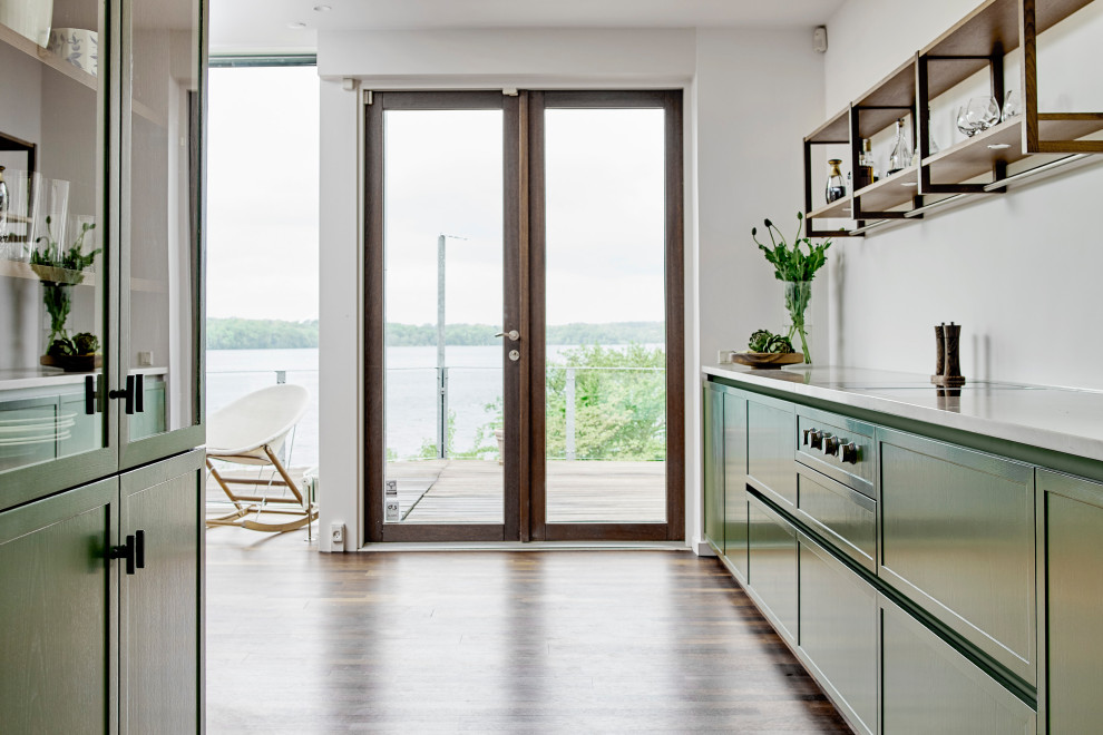Diseño de cocina minimalista de tamaño medio abierta con puertas de armario verdes, encimera de mármol, una isla, suelo marrón y encimeras blancas