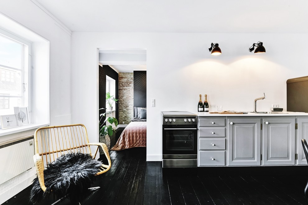 Aménagement d'une cuisine scandinave avec parquet peint, aucun îlot et un sol noir.