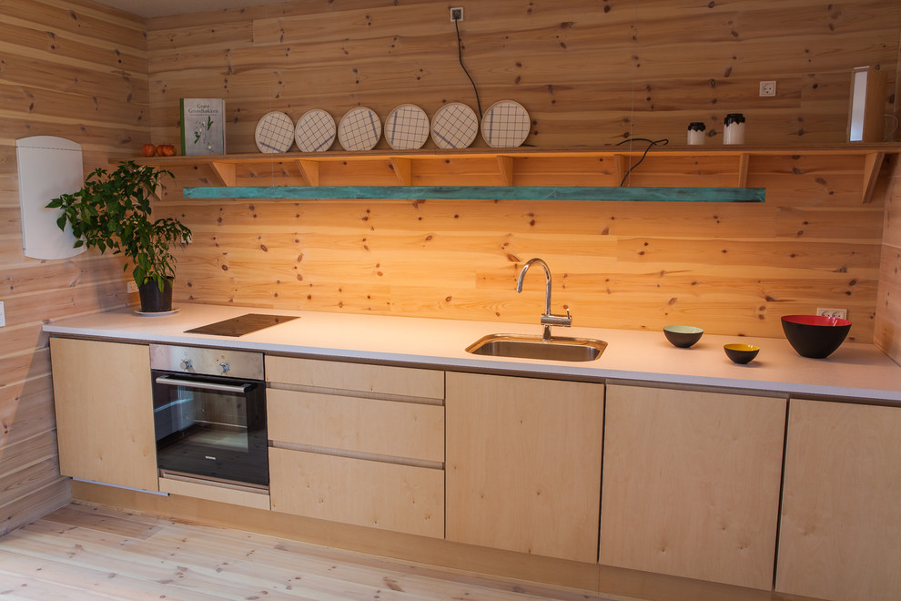 Cette image montre une cuisine linéaire nordique en bois clair avec un évier encastré, un placard à porte plane, parquet clair et aucun îlot.