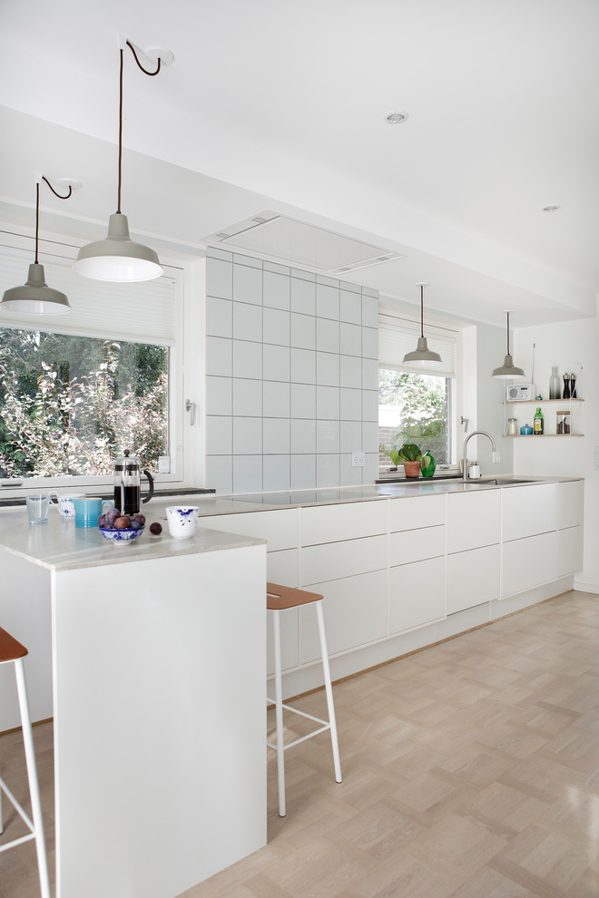 Idéer för att renovera ett mellanstort minimalistiskt l-kök, med släta luckor, vita skåp och en halv köksö