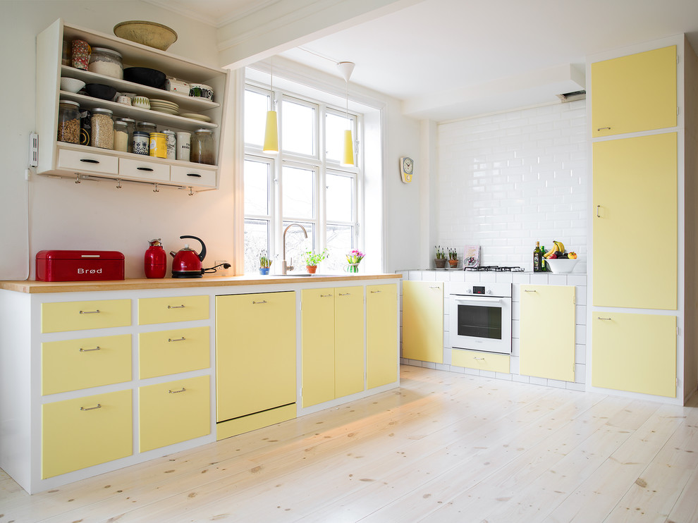Стильный дизайн: большая угловая кухня в скандинавском стиле с одинарной мойкой, плоскими фасадами, желтыми фасадами, белым фартуком, светлым паркетным полом и бежевым полом без острова - последний тренд