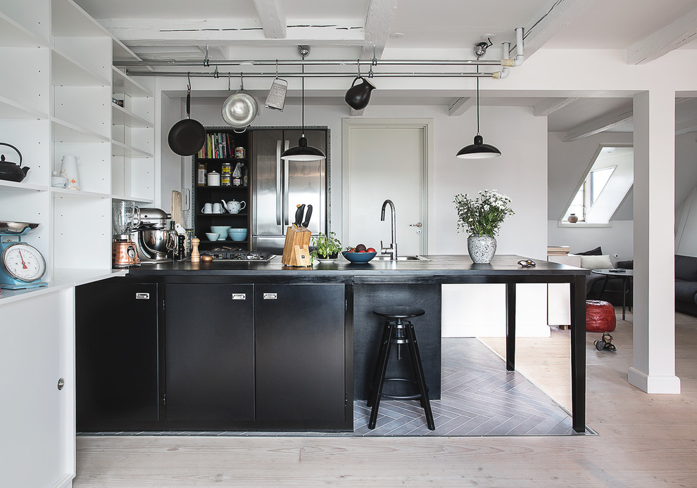 Exempel på ett minimalistiskt kök med öppen planlösning, med släta luckor, rostfria vitvaror, ljust trägolv och en halv köksö