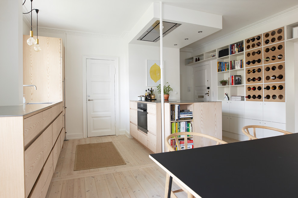 Ejemplo de cocina comedor nórdica de tamaño medio con armarios con paneles lisos, suelo de madera clara y península
