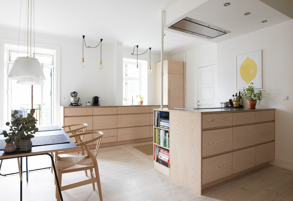 На фото: параллельная кухня среднего размера в скандинавском стиле с обеденным столом, плоскими фасадами, светлыми деревянными фасадами, светлым паркетным полом, полуостровом и бежевым полом с
