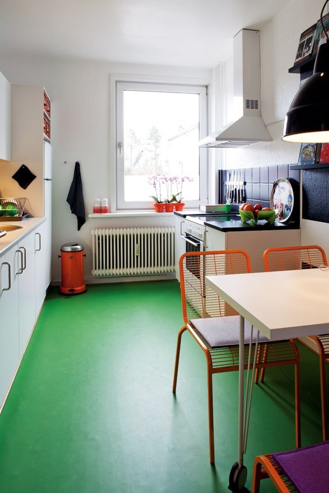 Diseño de cocina comedor nórdica sin isla con armarios con paneles lisos, puertas de armario blancas, salpicadero negro, salpicadero de azulejos de cerámica y suelo de cemento
