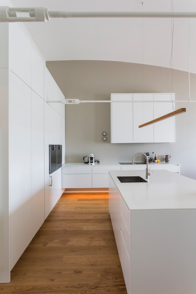 Стильный дизайн: кухня в скандинавском стиле с плоскими фасадами, белыми фасадами, черной техникой, паркетным полом среднего тона и островом - последний тренд