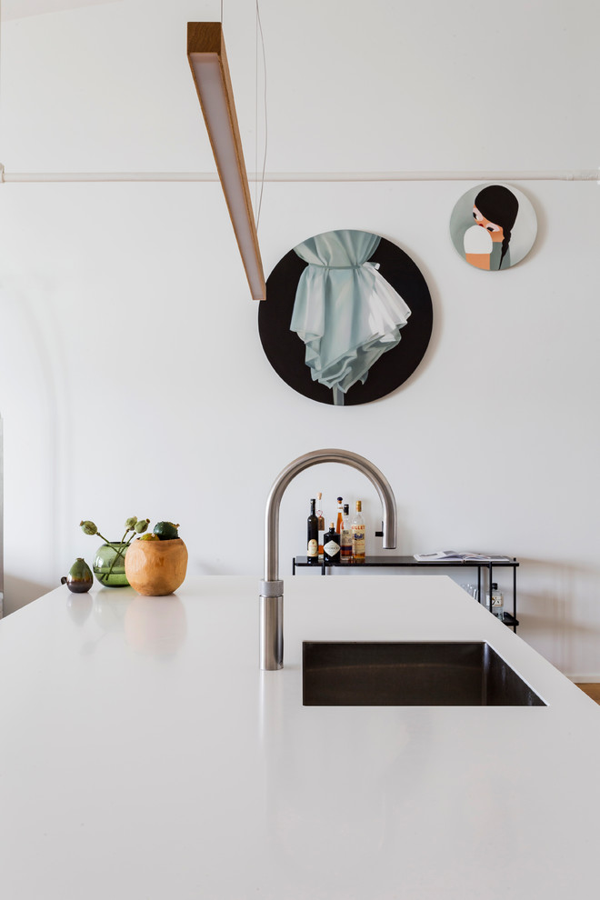 Ispirazione per un cucina con isola centrale nordico con ante lisce, ante bianche, elettrodomestici neri e pavimento in legno massello medio